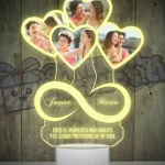 Una lampara led 3d con un objeto en forma de corazón e infinito con fotografias de personas.