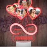 Una lampara led 3d con un objeto en forma de corazón e infinito con fotografias de personas.